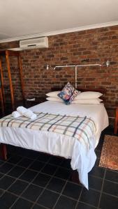 a bed in a room with a brick wall at Chargo River Lodge in Colesberg
