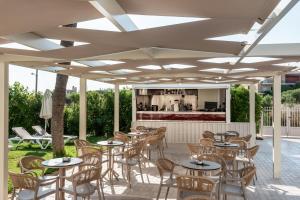 a patio with tables and chairs and a bar at Solimar Topaz - Adults Only in Tavronitis