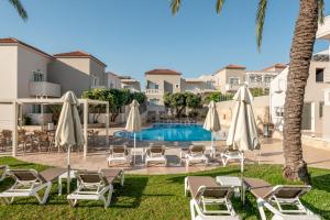 a pool with chaise lounge chairs and umbrellas at Solimar Topaz - Adults Only in Tavronitis
