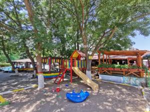 ein Spielplatz mit Rutsche in einem Park mit Bäumen in der Unterkunft Hotel Olymp in Sonnenstrand