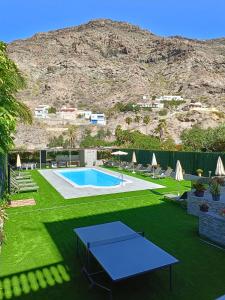 a pool with a table in a yard with a mountain at Mogan Sol in Puerto de Mogán