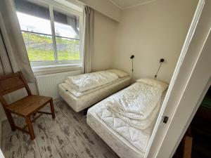a bedroom with two beds and a chair and a window at Gålåseter Jotunheimen 5 in Gålå
