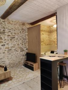 a room with a stone wall and a desk with a television at Jacuzzi de charme pour 2 in Nîmes