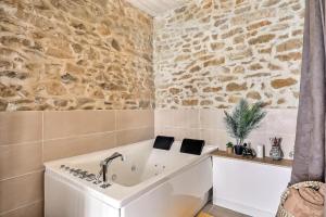 a bath tub in a bathroom with a stone wall at Jacuzzi de charme pour 2 in Nîmes