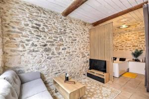 a living room with a couch and a stone wall at Jacuzzi de charme pour 2 in Nîmes