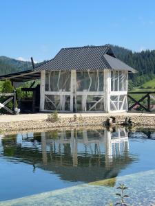 a white barn with a reflection in the water at Fazenda Fishbone, будиночок White fish in Verkhovyna