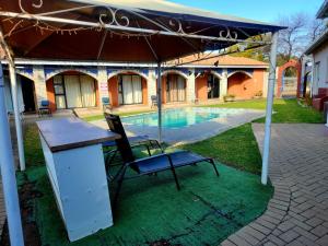 a table and a chair under a tent next to a pool at Villa Mexicana Guesthouse in Kimberley