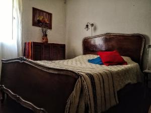 an old bed with a red pillow on it at la Casa de Susana in Tafí del Valle