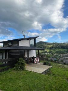 a house on top of a hill with a deck at Fazenda Fishbone, будиночок White fish in Verkhovyna