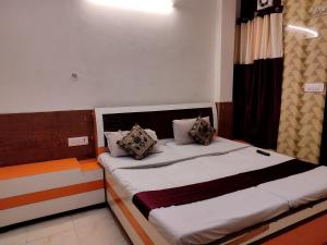 a bedroom with a bed with white sheets and pillows at Shraddha Hotel in Alīgarh