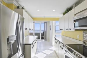 a kitchen with white cabinets and a stainless steel refrigerator at Two Bedroom Corner Condo with Panoramic Gulf Views in Clearwater Beach
