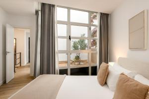 a bedroom with a white bed and a large window at MÁ HOMES Postigos in Málaga