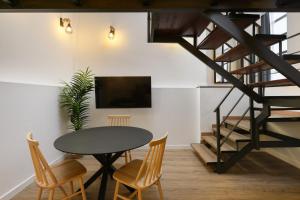 a dining room with a table and chairs and a tv at MÁ HOMES Postigos in Málaga