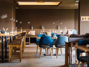 a restaurant with wooden tables and blue chairs at BE BIO Hotel be natural - direkt am Wasser in Tönning