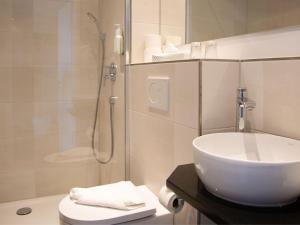 a bathroom with a white sink and a shower at BE BIO Hotel be natural - direkt am Wasser in Tönning +62 photos