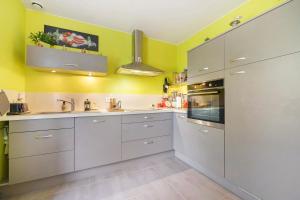 a kitchen with white cabinets and yellow walls at Le Lys De Mer - Chambre in Dragey