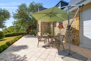 a patio with a table and chairs and an umbrella at Le Lys De Mer - Chambre in Dragey