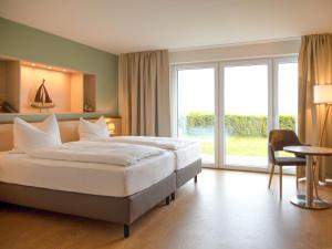 a bedroom with a large bed and a large window at BE BIO Hotel be natural - direkt am Wasser in Tönning