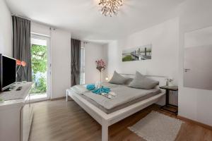 a white bedroom with a bed and a window at Ferienwohnung Annabelle in Bodman-Ludwigshafen