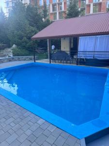 a large blue swimming pool in a yard at Zelena Sadyba Bila Stavka in Yaremche