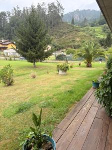 a wooden deck with a field of grass and trees at los jardines las rozas in Las Rozas