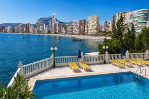 a swimming pool with chairs and a view of a city at Hotel Bossh Lido in Benidorm