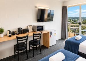 a hotel room with a bed and a desk with chairs at Lumina Motel Gladstone in Gladstone