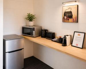 a counter with a microwave and a refrigerator on it at Lumina Motel Gladstone in Gladstone