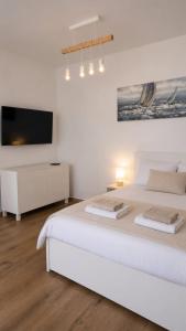 a white bedroom with a white bed and a flat screen tv at Family nest Medulin- apartment with private parking and jacuzzi in Medulin