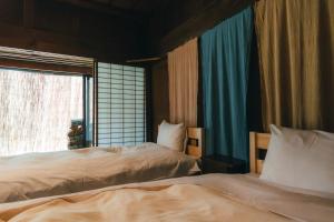two beds in a room with a window at Hostel Yui-an in Nagiso