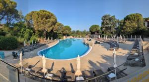 a large swimming pool with lounge chairs and umbrellas at Magiuli Village du Rouret in Grospierres