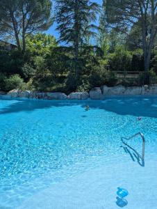 a swimming pool filled with blue water with trees at Magiuli Village du Rouret in Grospierres +11 photos