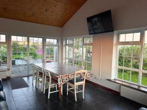 a dining room with a table and chairs and windows at Denmar Spacious coastal bungaow in Cleedagh Bridge