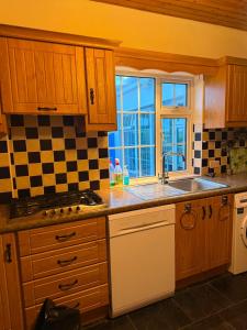 a kitchen with wooden cabinets and a sink and a window at Denmar Spacious coastal bungaow in Cleedagh Bridge