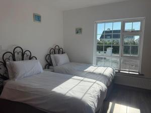 two beds in a room with a window at Denmar Spacious coastal bungaow in Cleedagh Bridge