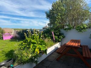 a wooden bench sitting in a garden next to a fence at Denmar Spacious coastal bungaow in Cleedagh Bridge +8 photos