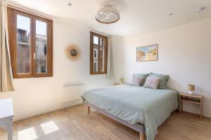 a white bedroom with a bed and two windows at Suite de La Dune - Studio - Hypercentre in Narbonne