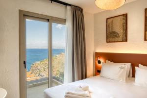 a hotel room with a bed with a view of the ocean at Soluna Forte Sea Living Suites in Palaiokastro