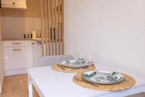 a white table with two plates and glasses on it at Suite de La Dune - Studio - Hypercentre in Narbonne