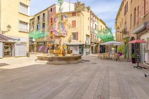 a fountain in the middle of a street with buildings at Suite de La Dune - Studio - Hypercentre in Narbonne +8 photos