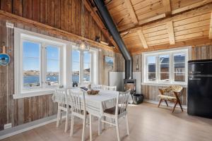 ein Esszimmer mit Tisch, Stühlen und Fenstern in der Unterkunft Åsebua - Renovated rorbu with seaview in Sørvågen