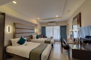 a hotel room with two beds and a desk and a television at Hotel Suba Galaxy Mumbai in Mumbai +33 photos
