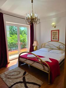a bedroom with a bed with a chandelier and a window at Vila Smarald Apartments in Neptun