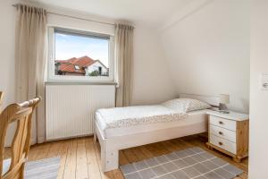 a white bedroom with a bed and a window at Ferienhaus nahe Uni Lueneburg in Lüneburg