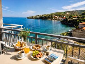 a table with food on a balcony with a view of the water at Nicolas in Chorto