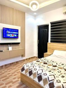 a bedroom with a bed and a flat screen tv at The Hideout in Lagos