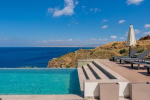 a pool with chairs and an umbrella and the ocean at Soluna Forte Sea Living Suites in Palaiokastro