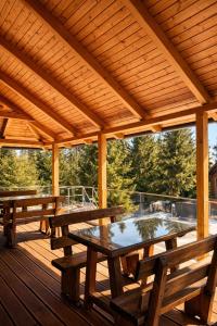 a wooden pavilion with wooden tables and benches on a deck at Transylvania Villa & Spa in Muntele Băişorii