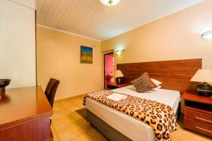 a hotel room with a bed and a desk and a table at Guest Paradise Lodge in Victoria Falls +58 photos