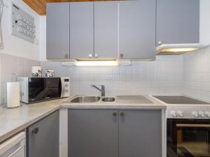 a kitchen with white cabinets and a sink and a microwave at Holiday Home Järvelä by Interhome in Kemijärvi +18 photos